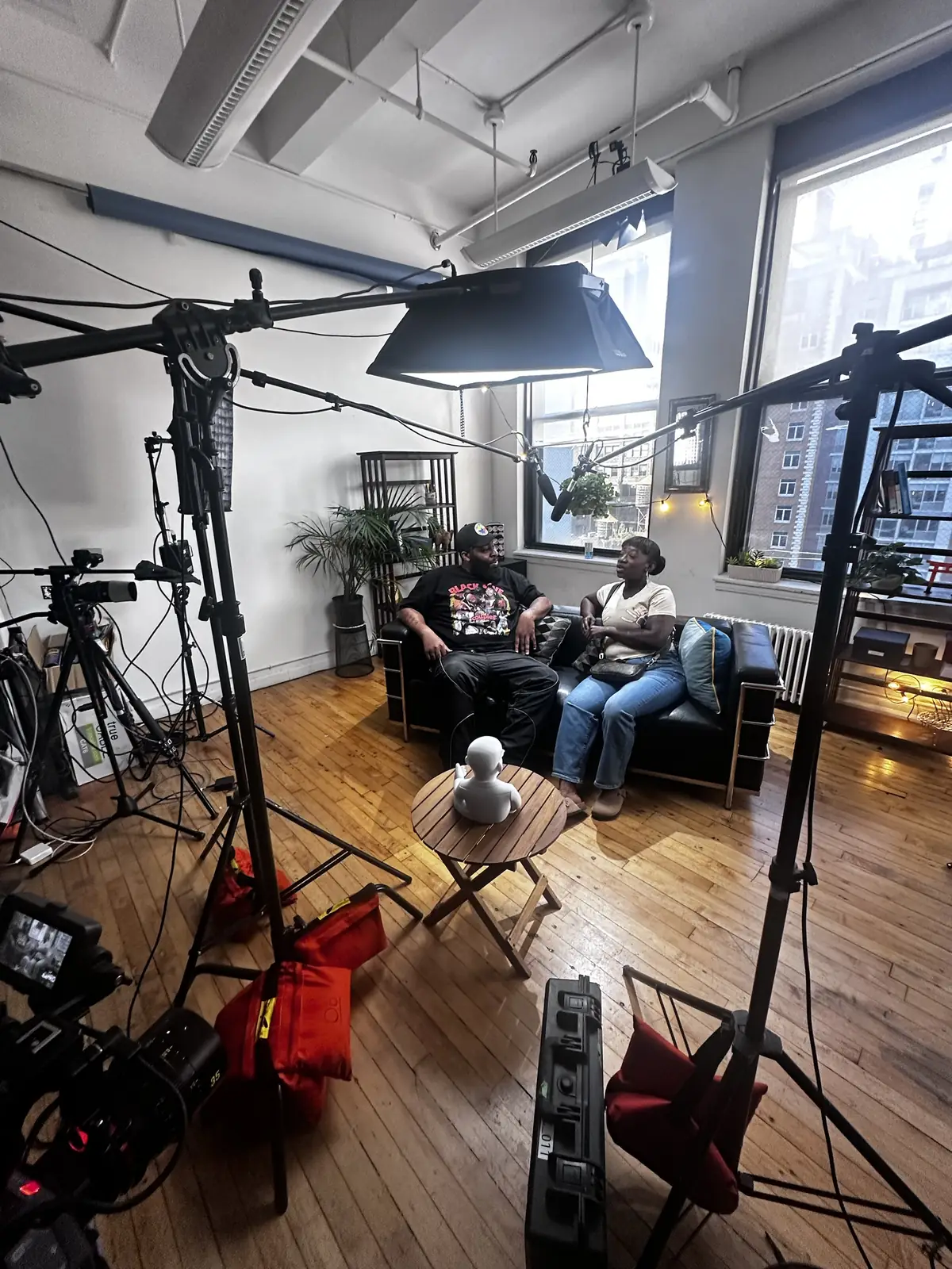 A couple in conversation on the AL the Show set, framed by lights, boom mics, and cameras