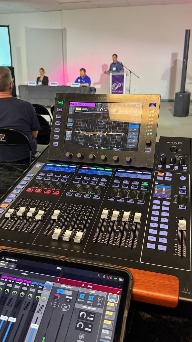 Audio and streaming console overlooking an event stage with podium and screen