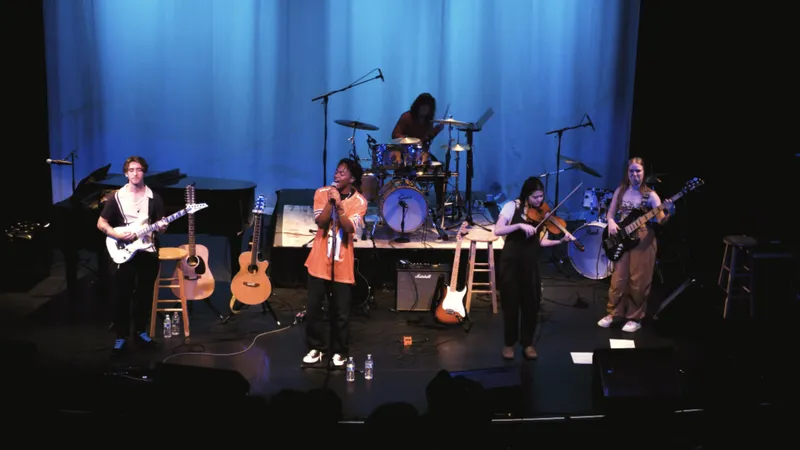 A band performing on a theater stage under blue light