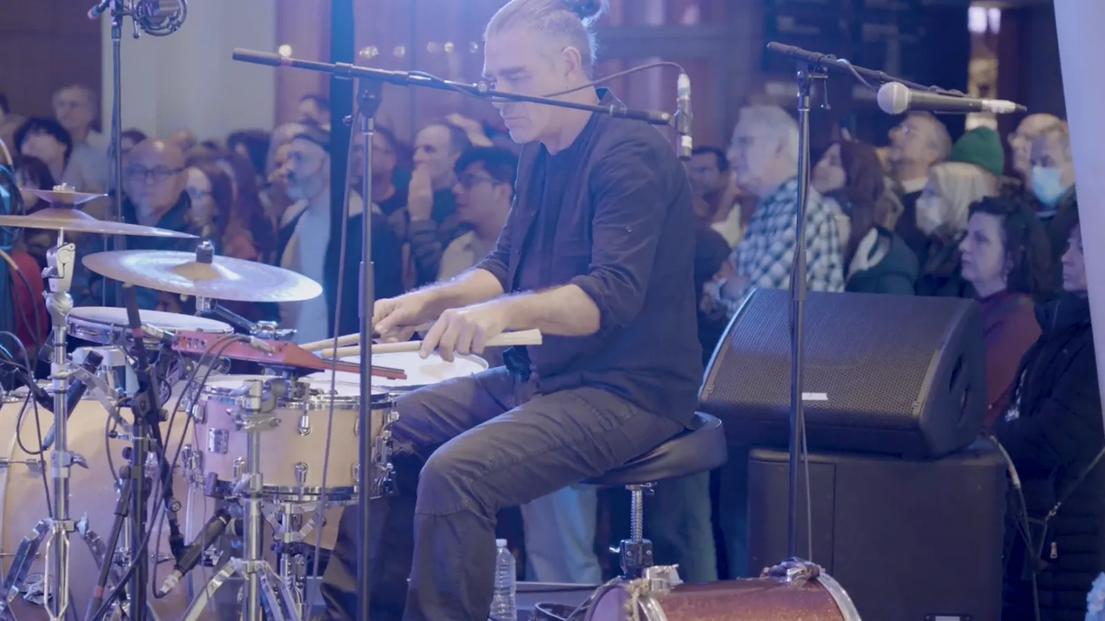 A drummer playing in front of a standing crowd at a concert