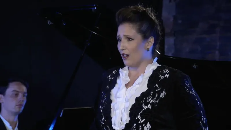 A soprano singing beside a grand piano with the pianist behind her
