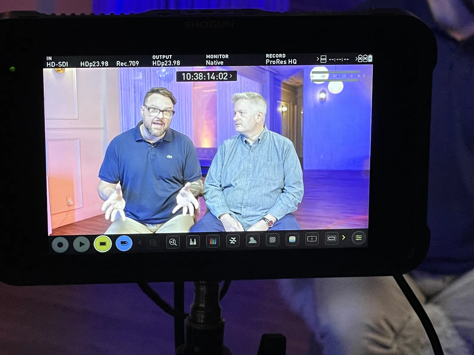 A field monitor showing two men seated for an on-camera interview