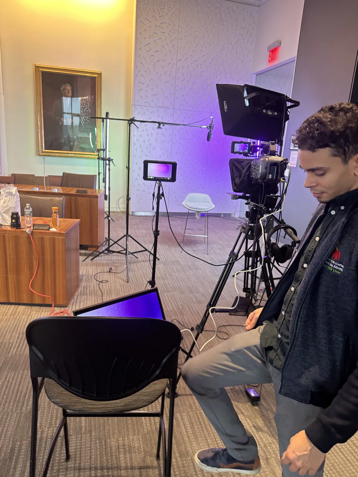 A camera operator checking a shot on a multi-camera set with monitors and lights in a bright room