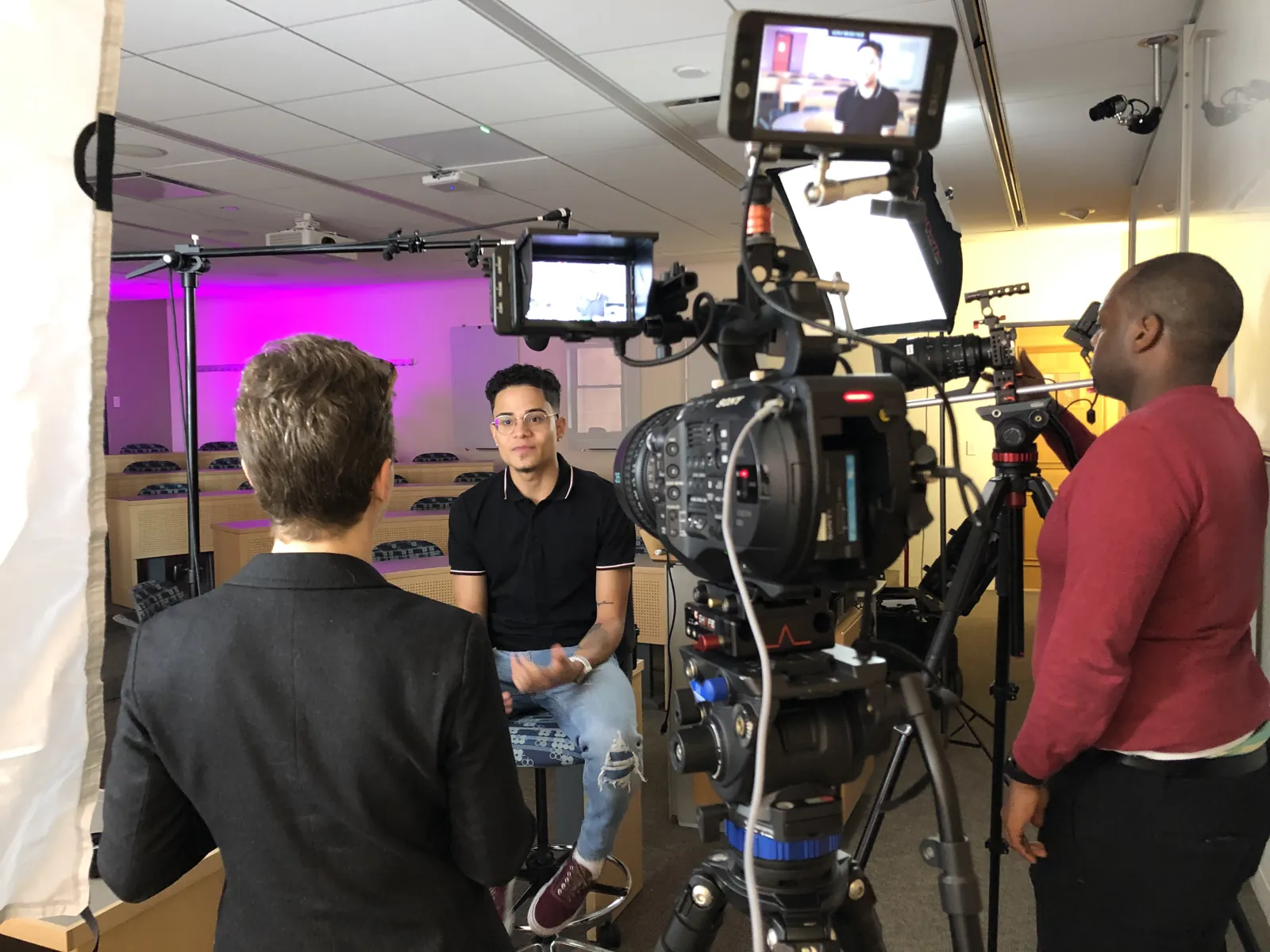 Transcendent crew on two cameras filming a corporate interview against a lit backdrop