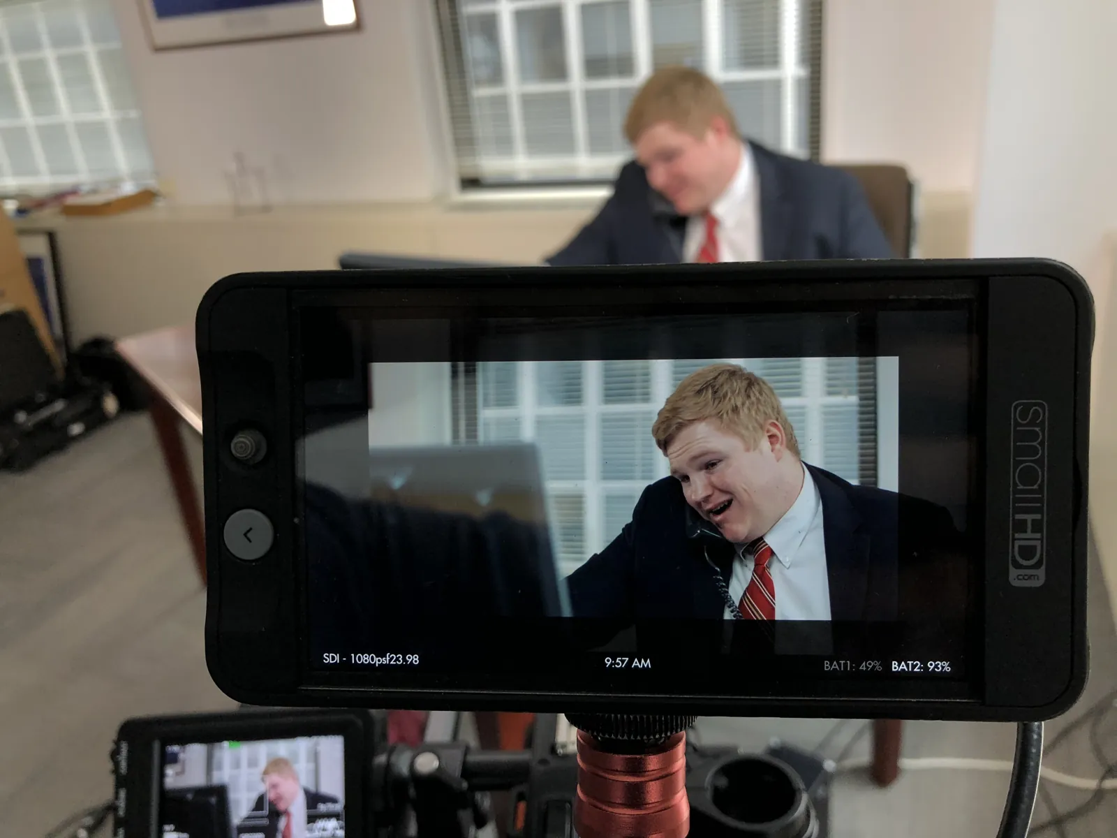 A camera monitor showing an executive in a suit and tie mid-interview