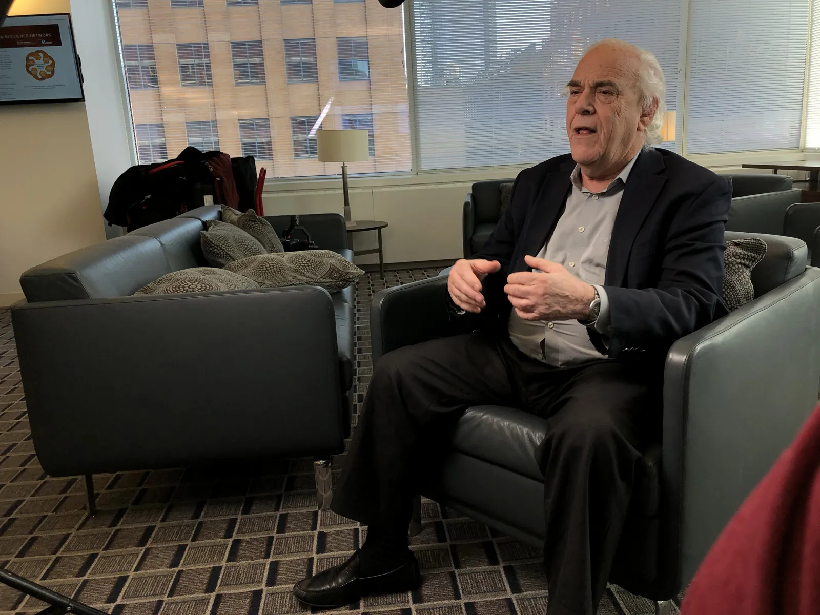An executive in a suit being interviewed on a sofa in a Manhattan office