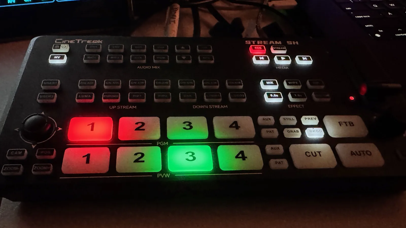 A live production switcher with program and preview buttons lit red and green