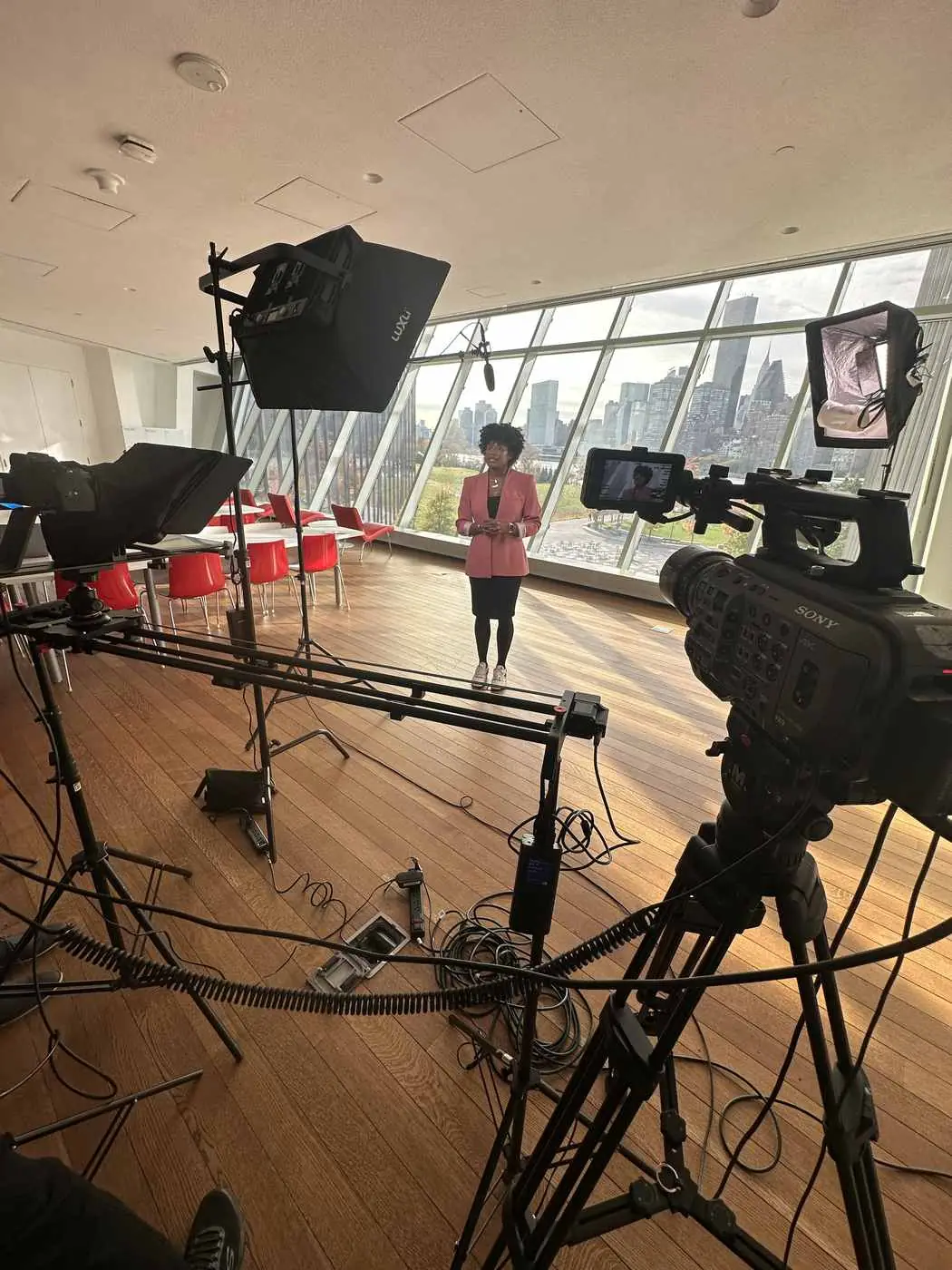 Executive video setup with camera slider, teleprompter, and skyline backdrop at a university campus