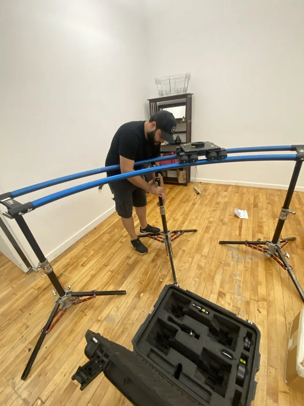 A crew member assembling a curved dolly track on stands in the studio